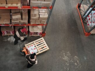 Pracownicy w magazynie transportują ładunek wózkiem paletowym