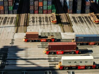 Transport kontenerów morskich za pomocą pojazdów terminalowych w porcie przeładunkowym.